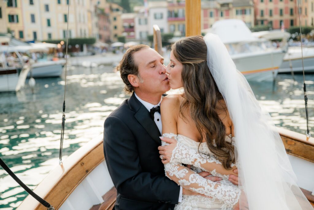 Couple kissing on a traditional Ligurian gozzo with Portofino harbour in the background — portofino elopement at Belmond Hotel Splendido